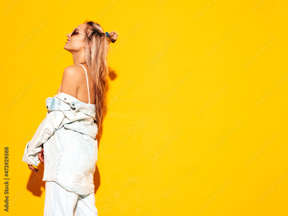 Portrait of young beautiful smiling blond female in trendy summer clothes. Sexy carefree woman posing near yellow wall in studio. Positive model having fun indoors. Cheerful and happy in sunglasses Portrait of young beautiful smiling blond female in trendy summer clothes. Sexy carefree woman posing near yellow wall in studio. Positive model having fun indoors. Cheerful and happy in sunglasses