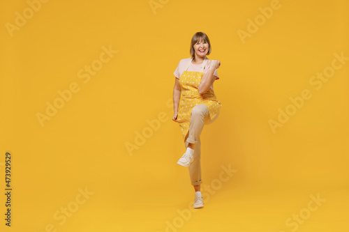 Full body elderly overjoyed excited fun satisfied housekeeper housewife woman in orange apron do winner gesture isolated plain on yellow background studio portrait People household lifestyle concept