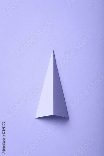 color of year 2022 - Very Peri. minimal lilac background with paper shape. purple christmas tree with copy space.