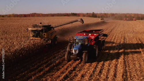 4K AERIAL FOOTAGE OF COMBINE OPERATION WITH SUPPORTING TRACTORS REAPING WEATH IN QUEBEC CANADA photo