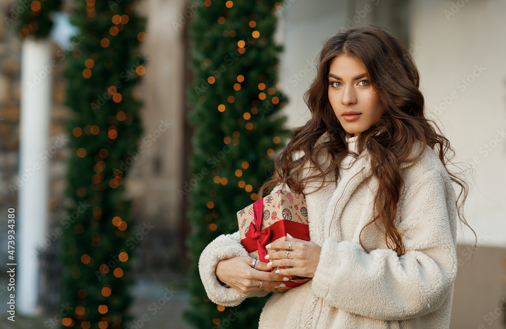 A young beautiful woman with a gift in her hands on the street
