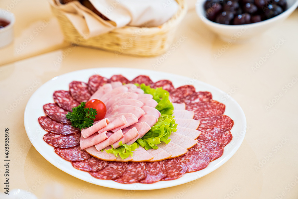 round white plate with chopped sausage, meat, lettuce, herbs and tomato. snack for the festive table. meat products store. round white plate with chopped sausage, meat, lettuce, herbs and tomato. snack for the festive table. meat products store.