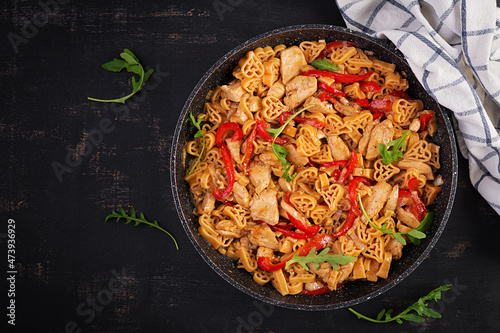 Heart-shaped pasta in tomato sauce with chicken and sweet pepper with arugula on a dark table. Top view