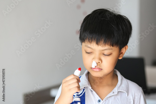 An Asian young boy using tissue to stop the nose bleeding.  photo