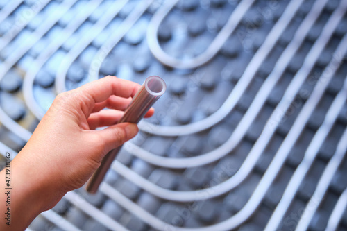 Hand holding a polyethylene pipe used for radiant underfloor system.