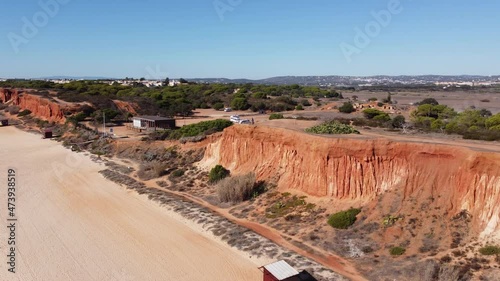 Aerial shot of praia da Rocha Baixinha in the Algarve following a cyclist who stands still on the dunes, sunny morning light. Flying with a half circle around the cyclist. Europe Portugal photo