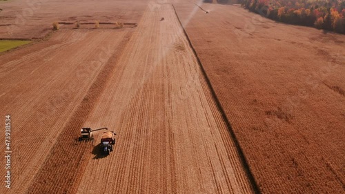 4K AERIAL FOOTAGE OF COMBINE OPERATION WITH SUPPORTING TRACTORS REAPING WEATH IN QUEBEC CANADA photo