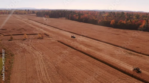 4K AERIAL FOOTAGE OF COMBINE OPERATION WITH SUPPORTING TRACTORS REAPING WEATH IN QUEBEC CANADA photo