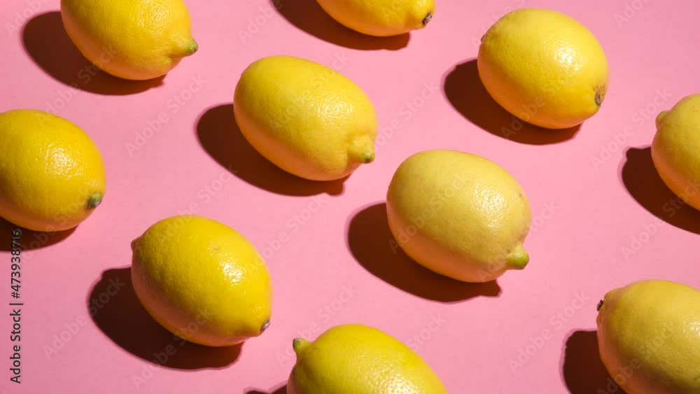 Stop motion. Movement of lemons on a pink background diagonally in different directions. Lemons on a pink background are moving in different directions. Abstract background.