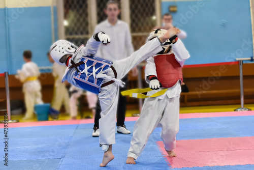 Kids fighting on stage during Taekwondo tournament. Blurred background