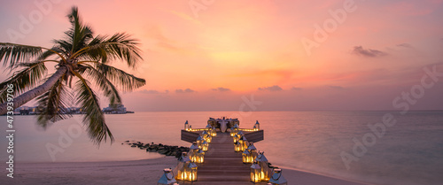 Romantic dinner on the beach with sunset, candles with palm leaves and sunset sky and sea. Amazing view, honeymoon or anniversary dinner landscape. Exotic island evening horizon, romance for a couple
 photo
