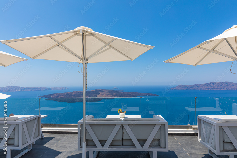 Fototapeta premium Beautiful sunny blue sky at Santorini island, Greece. Lounge chairs with umbrellas on the terrace with sea view. Travel destinations concept. Luxury summer destination, amazing landscape, Aegean sea