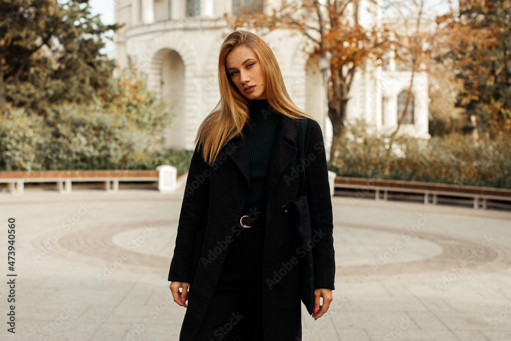 A young beautiful woman in a black coat walks around the city A young beautiful woman in a black coat walks around the city