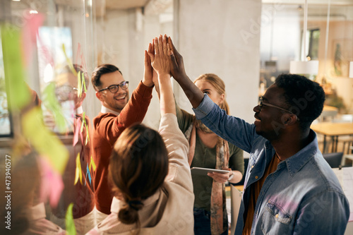 Happy multi-ethnic start-up team uniting their hands during business meeting at casual office.