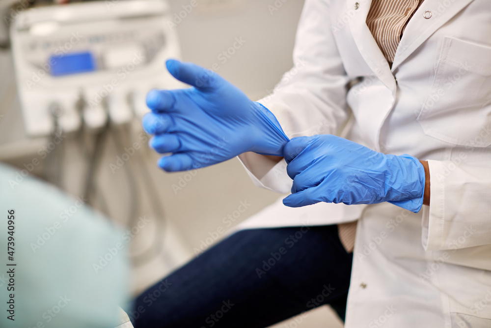 Close-up of dentist uses surgical gloves while working at dental clinic. Close-up of dentist uses surgical gloves while working at dental clinic.