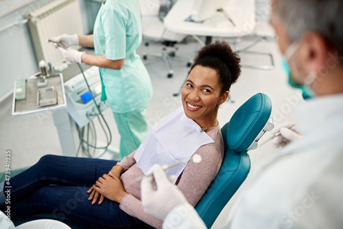 Happy African American woman talks to dentist during appointment at dentist's office.