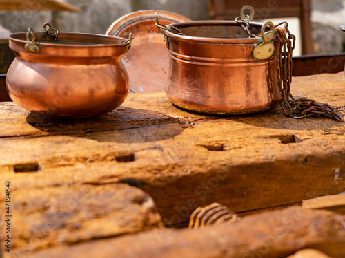 Close-up of vintage copper cauldrons on antique carpenter workbench