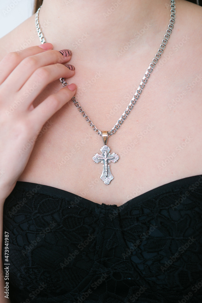 Trendy silver cross and chain on a beautiful young girl. Beauty and fashion 
