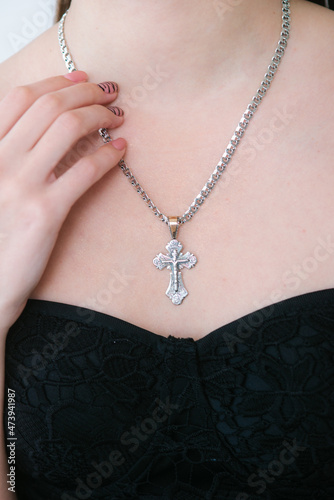 Trendy silver cross and chain on a beautiful young girl. Beauty and fashion 