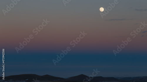 The moon in the setting cloudy winter sky