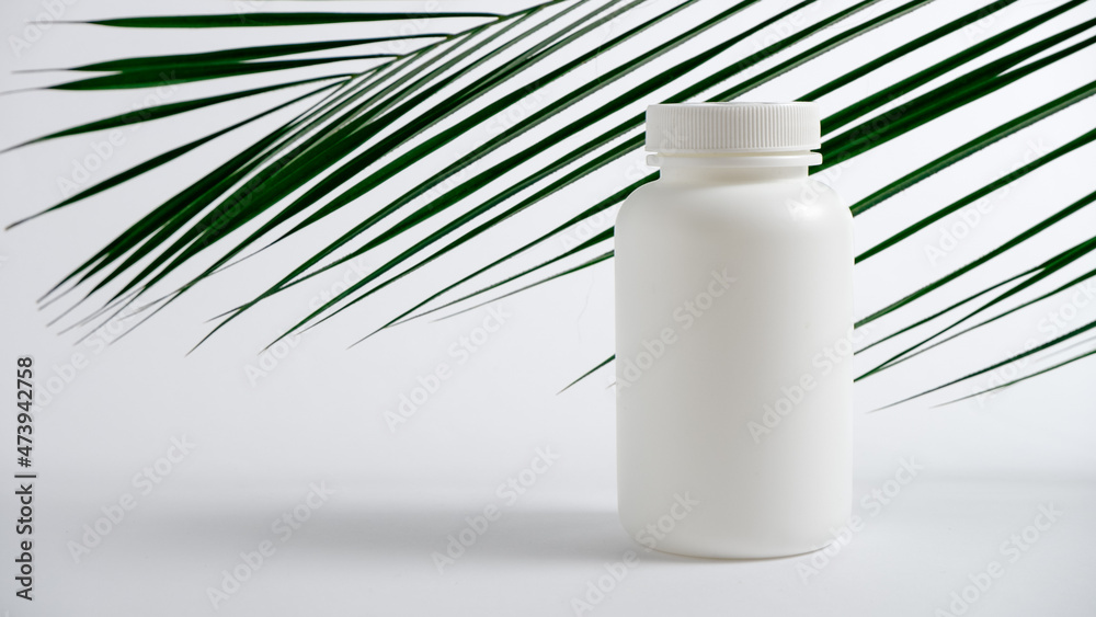 Mockup. White plastic bottle for vitamins, cosmetics, health care products on a white background with green palm leaves. Cosmetic medical beauty product Mockup. White plastic bottle for vitamins, cosmetics, health care products on a white background with green palm leaves. Cosmetic medical beauty product