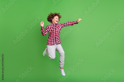 Full length body size view of attractive cheerful trendy guy jumping good mood isolated over bright green color background