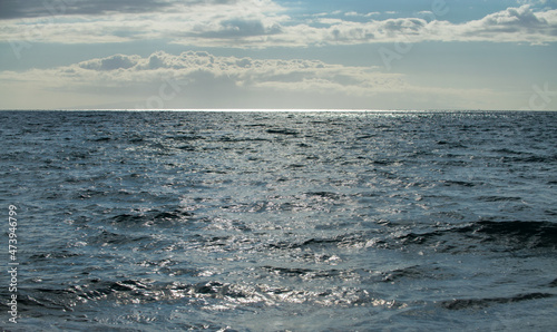 Summer sea background. Texture of water surface. Shining blue water ripple pattern.