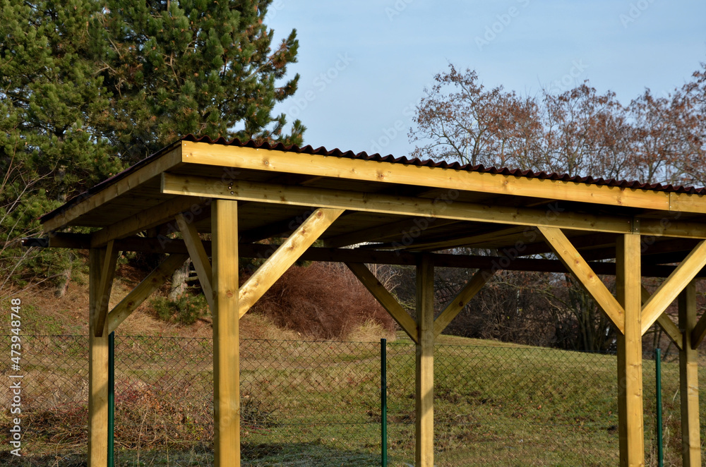 cheap wooden pergola in the meadow serves as a shelter for the playground in the housing estate. flat roof, yellow wooden columns with reinforcement