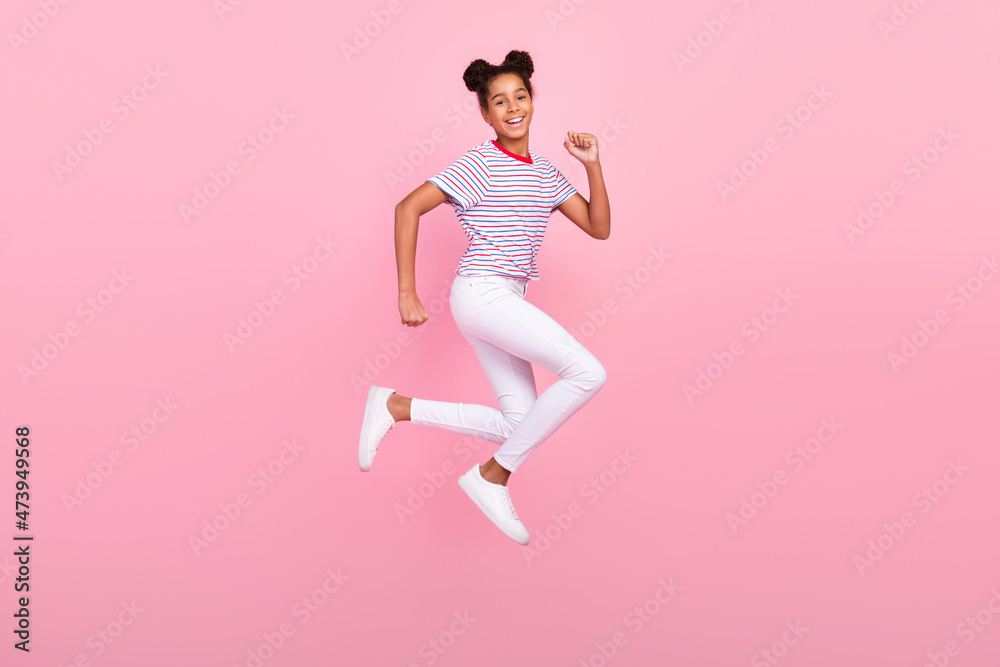 Full body photo of childhood african american brunette haired stylish trendy girl wear casual clothes jump run isolated on pink color background Full body photo of childhood african american brunette haired stylish trendy girl wear casual clothes jump run isolated on pink color background