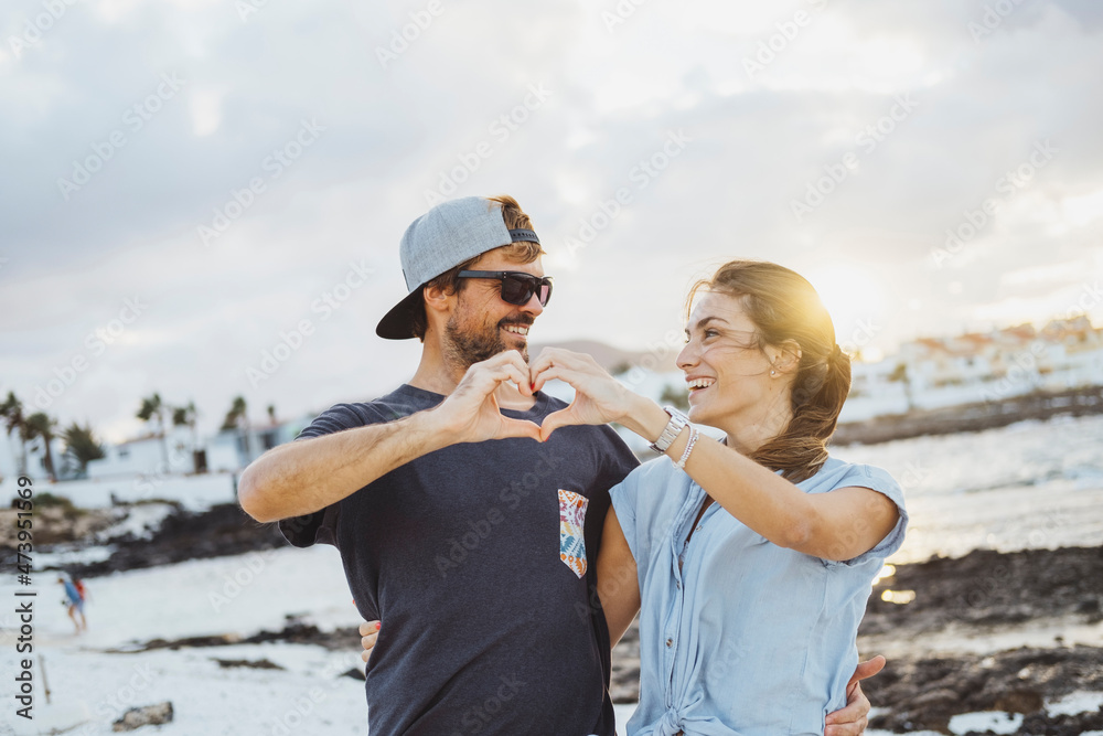 Smiling couple making heart with hands at beach Smiling couple making heart with hands at beach