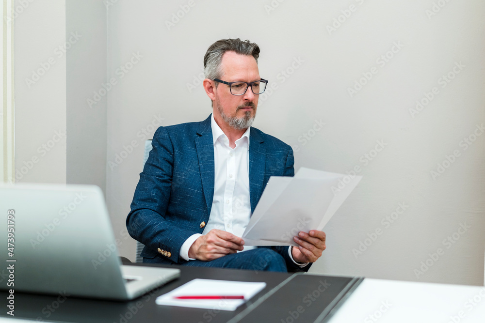 Male professional checking document while sitting at office Male professional checking document while sitting at office