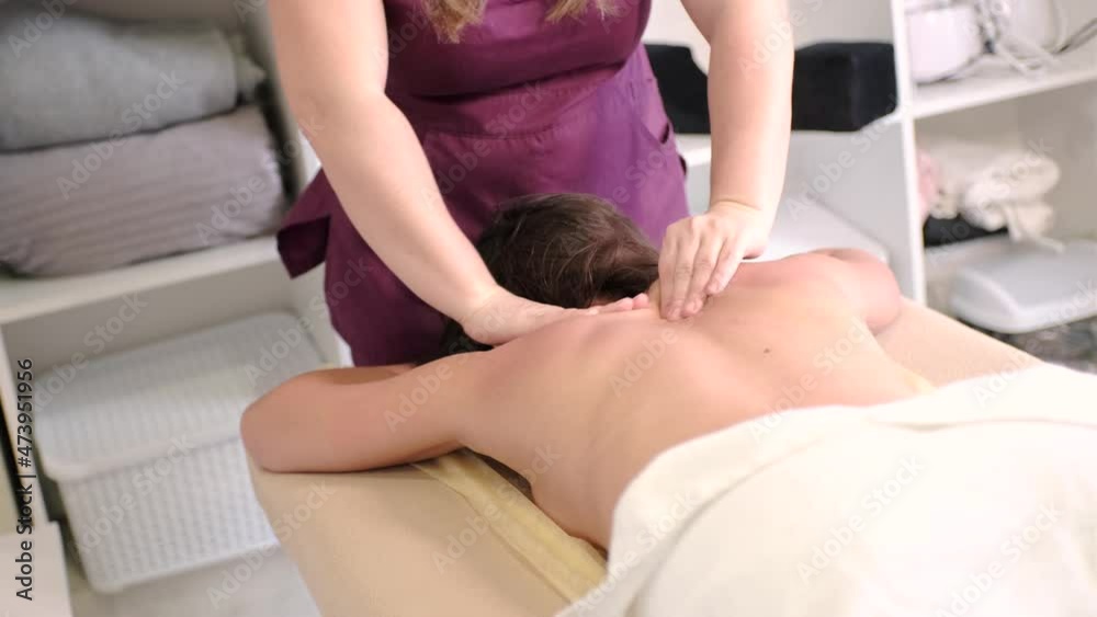 Close-up young woman massage therapist making back massage to a relaxed woman in spa salon Close-up young woman massage therapist making back massage to a relaxed woman in spa salon
