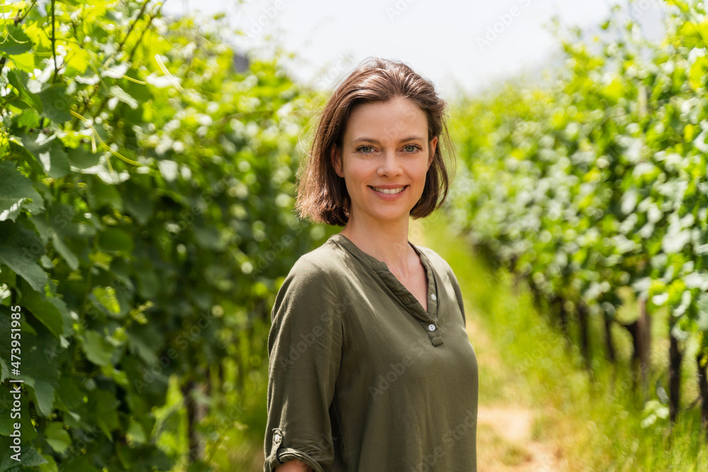 Smiling woman standing at vineyard during sunny day Smiling woman standing at vineyard during sunny day