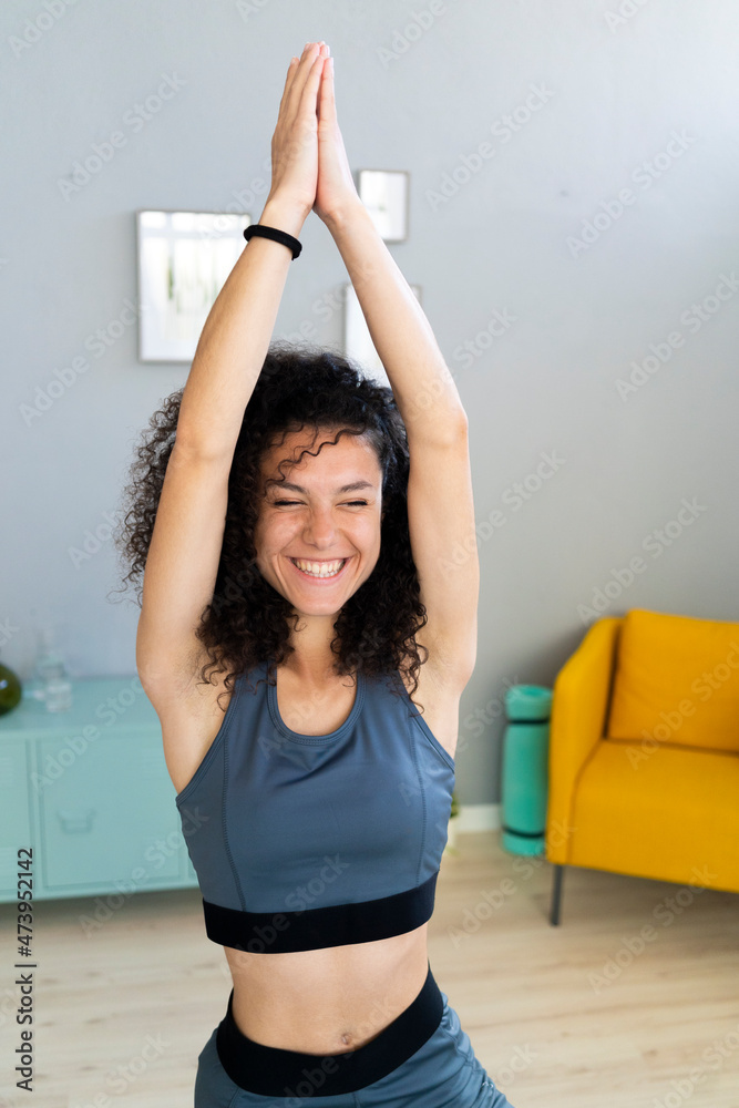 Smiling woman with hands clasped looking away while practicing yoga at home Smiling woman with hands clasped looking away while practicing yoga at home