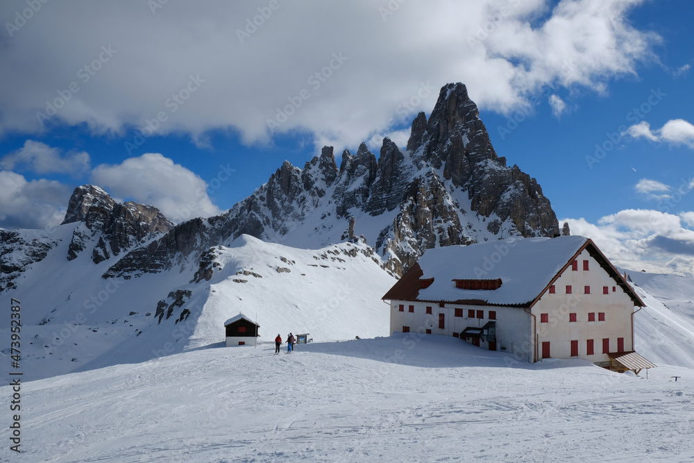 Beautiful panorama of Tre Cime di Lavaredo and Monte Paterno in sunny winter scenery. Locatelli hut and chapel at foot of mountains. Tre Cime, Dolomites, Italy