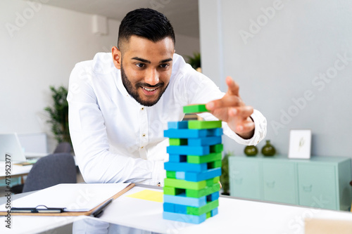 Smiling male entrepreneur holding toy block at office photo