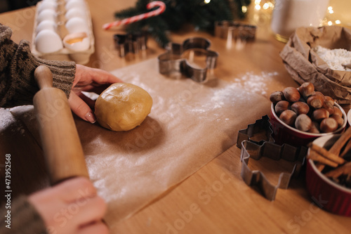 Woman using rolling pin for making gingerbread. Close-up of rolling raw dough for gingerbread. Christmas mood. Preparing for hollidays photo