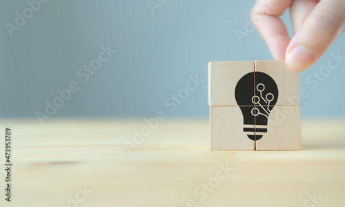 Ideas of innovation and technology concept. High value added product and service for business strategy. Hand puts the wooden cubes; light bulb with technology icon inside. Grey background, copy space.