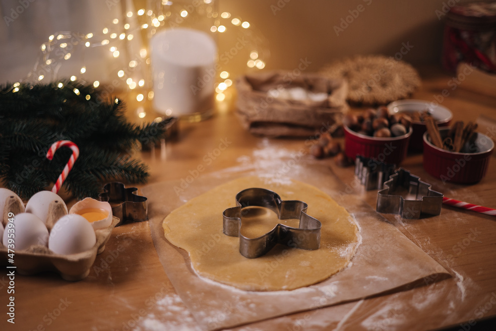 Home bakery, cooking traditional festive sweets. Cutting cookies of raw gingerbread dough on wooden table. New Year celebration traditions. Christmas mood Home bakery, cooking traditional festive sweets. Cutting cookies of raw gingerbread dough on wooden table. New Year celebration traditions. Christmas mood