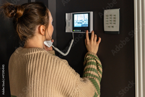Woman using intercom device at home photo