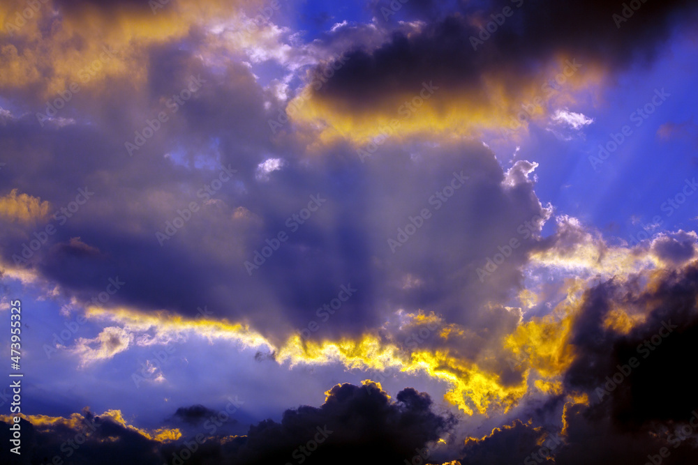 Bright rays of the sun shine through dramatic clouds.