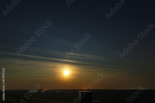 The ascending moon shines through the clouds on the observation platform. © lexuss