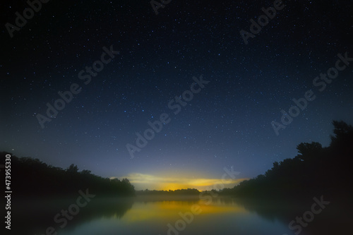 Night sky with bright stars over the river with fog. Summer landscape in Russia.