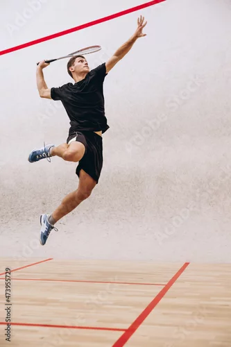 Obraz Full-length portrait of sportive boy training, playing squash in sport studio