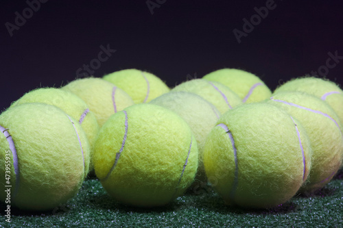 Sport Concepts. Variery of Lawn Tennis Balls on Green Grass Surface Placed Bulk Over Black Background. photo