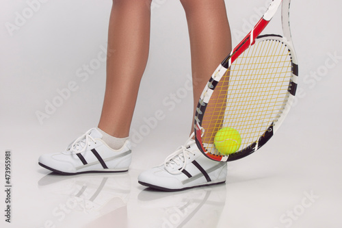 Sport Ideas. Legs of Caucasian Female Lawn Tennis Player Holding Green Tennis Ball With Raquette. Over White.