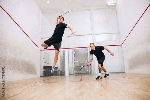 Full-length portrait of two young sportive boys training together, playing squash isolated over sport studio background photo