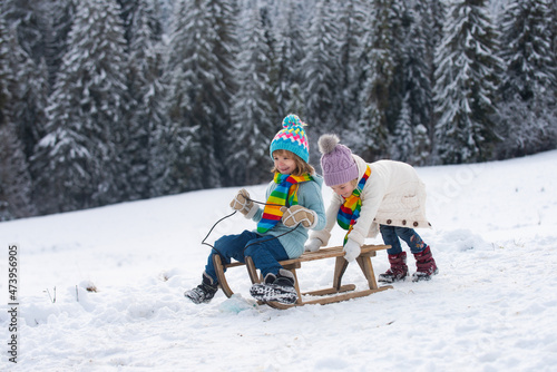 Foto Happy little boy and girl sledding in winter