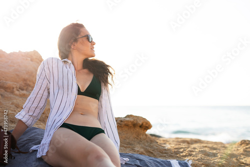 Happy young woman relaxing on the sandy beach. Beautiful woman enjoying a summer day on the beach..