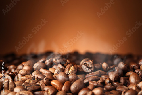 Heap of aromatic roasted coffee beans on brown background, closeup © New Africa